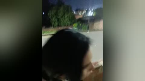 A blurred video shows a person with dark hair, possibly Asian, bending over, with a dimly lit outdoor setting in the background.