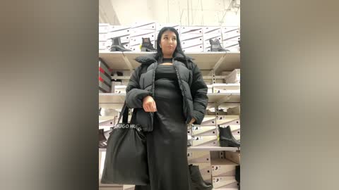 Media: Video of a woman in a black coat, dress, and handbag, standing in a shoe store with white shelves holding shoes.