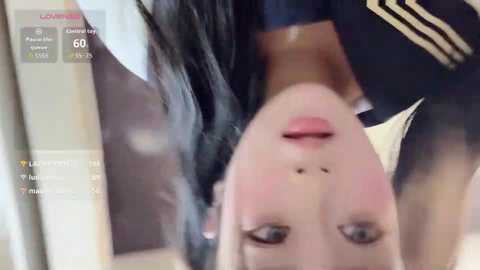 Media: Video of a woman with long black hair and fair skin, wearing a white top and black jacket, captured in a selfie, showing her upside-down face.