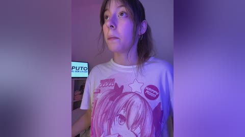 Video of a young woman with straight brown hair, wearing a white T-shirt with a cartoon character, holding a \"Puto\" sign, in a dimly lit room with purple and blue lighting.