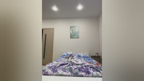 Video of a minimalist bedroom with a bed covered in a floral duvet, beige wardrobe, and abstract wall art in pastel colors, creating a serene and modern atmosphere.