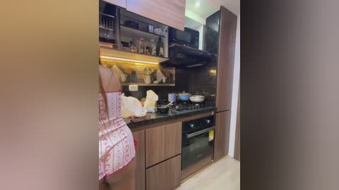 A video of a modern kitchen with dark wood cabinets, stainless steel appliances, and a white apron hanging on the left.