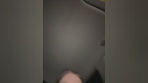 Media: A blurry, low-resolution video shows a person's face obscured by a dark object, likely a hat or hair, in a dimly lit, possibly indoor setting with muted tones.