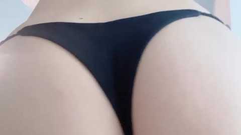 A close-up video of a woman's buttocks in black thong underwear, featuring smooth, light skin and a clear focus on the curves and contours of her lower body.