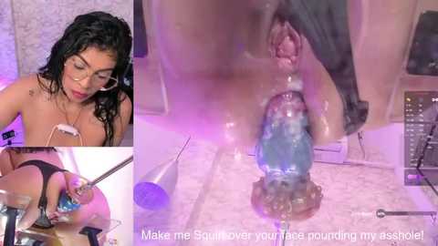 A video of a woman with wet, curly black hair, wearing glasses and a black bra, inserting a blue dildo into her anus. Background includes a bathroom with a marble floor and purple lighting.