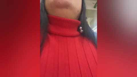 A video of a person wearing a bright red turtleneck sweater, partially obscured by red and white vertical stripes. The background is blurry, suggesting an indoor setting.