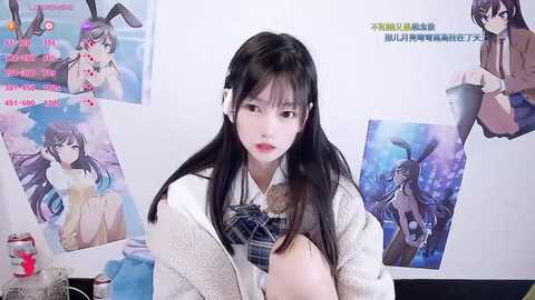 Media: Video of a young East Asian woman with long black hair, wearing a white cardigan and plaid tie, surrounded by anime posters and a cluttered desk.