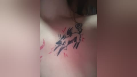 A close-up video of a person's shoulder displaying a black tattoo of a stylized dog with a swirling tail, surrounded by red hearts and abstract brush strokes. The skin tone is light.