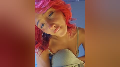 A video of a young woman with vibrant red hair, light skin, and a slender physique, wearing a light-colored bra, looking directly into the camera with a neutral expression.