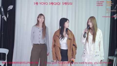 Video of three women on a white background, each with long hair, in casual outfits, speaking into microphones. Korean text and \"YOYO3QI\" branding visible.