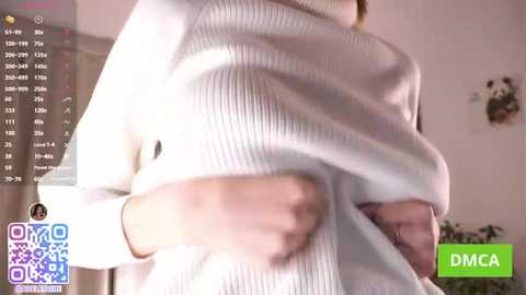 Video of a person in a white, ribbed sweater, capturing their side profile with a hand on their waist. Background shows a wall with a panda picture and a green \"DMCA\" watermark.