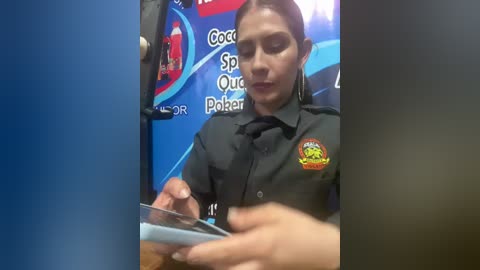 Video of a young woman with dark hair in a black police uniform, holding a tablet, against a blue and red background with \"Cops\" and \"O.R.\" text.