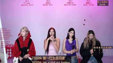 Video of four young women in casual clothes, seated in front of a light pink backdrop with Chinese text. They hold microphones, appearing serious and focused.