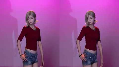 Video of a young, slim, light-skinned woman with blonde hair in a red short-sleeved top and denim shorts, standing against a purple backdrop. She holds an orange ball in each hand.