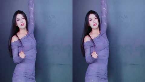Video of an Asian woman with long black hair, wearing a sheer purple lace dress, posing with arms stretched upward against a dark grey wall.