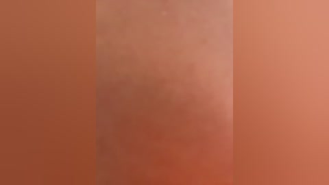 A blurred video of a person's lower back, showing a light skin tone, with slight shadows and a warm, reddish-brown background.