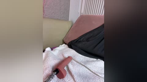 A video shows a person lying on a bed with a white blanket, black pillow, and red cane handle visible. The background includes a beige wall and white radiator.