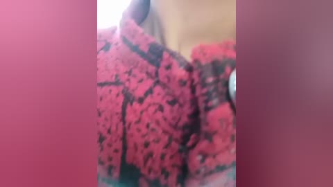 Media: A blurry video showing a woman in a pink, leopard-print dress, with a blurred background of a beige wall. The focus is on the fabric's texture and pattern.