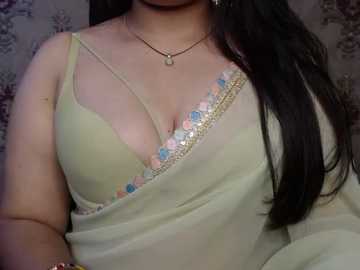 Video of a woman with long dark hair, wearing a pale yellow sari with a floral embroidered border, revealing a pink bra underneath.