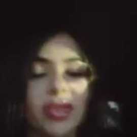 A blurred video shows a young woman with closed eyes, slightly open mouth, and dark hair. Her skin is pale, and she appears to be in a dimly lit room.