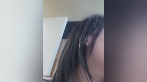 Video of a close-up of a person's head, showing messy dark hair, possibly female, with a blurry background.