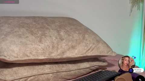 A video of a woman with blonde hair and a purple shirt, wearing headphones, sleeping with a pillow on her head in a dimly lit bedroom.