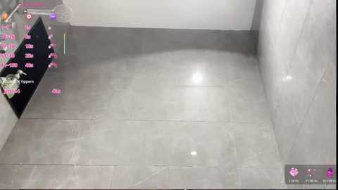 A video of a modern bathroom with large, grey, glossy tiles. The room is empty, and the lighting is bright and even. There are no visible objects or furniture.