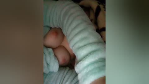 Video of a person's hand holding a light blue, textured blanket, with a hint of a breast visible beneath the blanket, suggesting a close-up, possibly intimate setting.