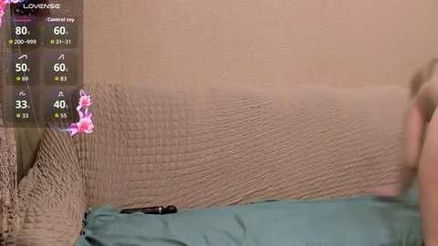 A video shows a beige sofa covered in a textured, light brown blanket with a green pillow. The background is a beige wall. An augmented reality interface overlaid on the left displays weather and temperature information.