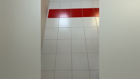 A video of a white-tiled ceiling with a horizontal red stripe, set against a plain, light-colored wall, creating a minimalist and clean aesthetic.