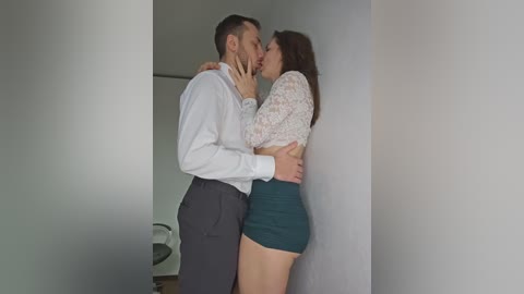 Video of a white couple in an intimate embrace; man in a white shirt, woman in a lace top and high-waisted skirt, both with light skin tones.