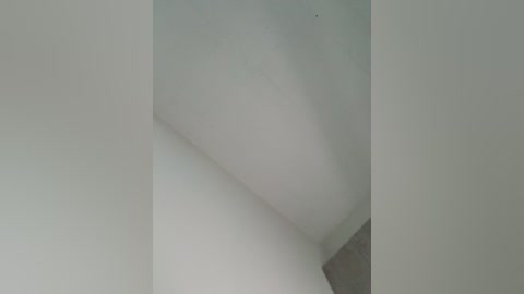 A video of a minimalist interior featuring a corner of a white wall with smooth texture and a slight shadow, creating a clean and modern aesthetic.