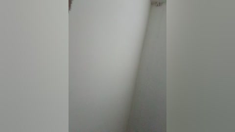 A video of a white wall with a subtle, diagonal crack extending from the top left corner to the bottom right, creating a subtle shadow. The background is plain and unadorned, with no other objects or colors.