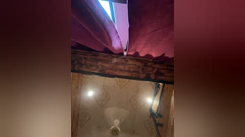 A video of a dark, dimly lit room with a sloped ceiling, featuring two bright lights and a small window at the top, creating a warm, intimate atmosphere.