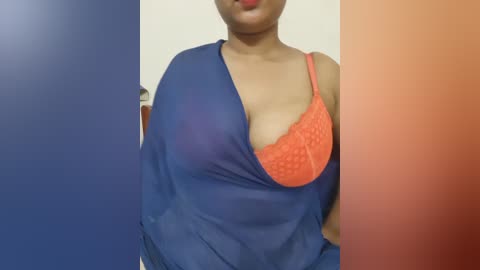 Video of a dark-skinned woman wearing a sheer blue top with an orange lace bra visible underneath, her lips painted red.