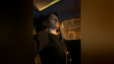 Video of a woman in a black hat and coat, leaning against a vintage car with dim interior lighting.