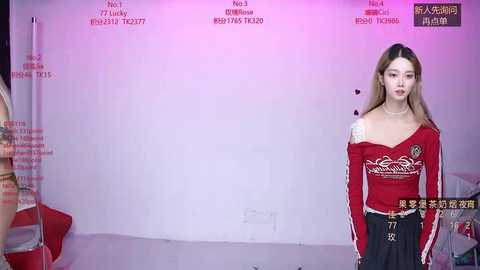 Video of a young woman with fair skin and long brown hair in a red, off-the-shoulder top and black pants, standing in front of a white backdrop with text in Korean and English.
