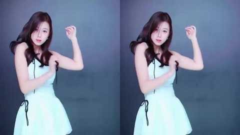 Media: Video of an East Asian woman with long brown hair, wearing a white strapless dress, posing with clenched fists against a plain gray backdrop.