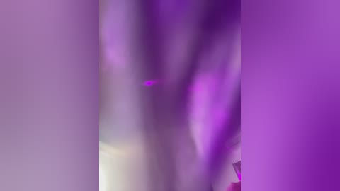 This is a blurred, abstract digital image featuring soft, swirling colors of purple and pink, giving a dreamy, ethereal vibe. The image has a smooth, almost liquid texture.