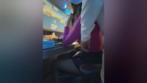 Video of a woman in purple leggings and white shirt, leaning over a dark counter, with a man in a white shirt and black pants standing behind her.