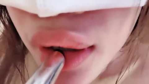 A close-up video of a person's mouth with a metallic dental instrument inserted into their gums, revealing red, inflamed tissue. The individual's face is partially obscured by a white towel.