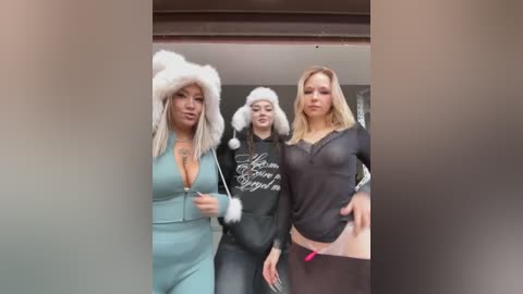 Video of three women: one in a furry hat and light dress, another in a black hoodie, and a third in a sheer top, all smiling and walking together.