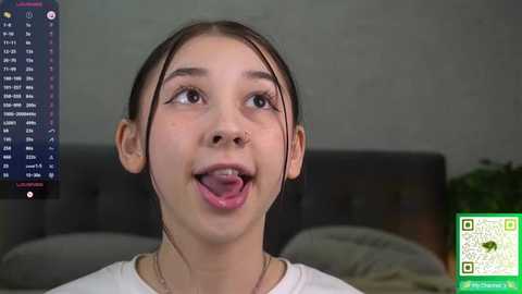 Media: A video of a young woman with fair skin, brown hair, and a white shirt, sticking her tongue out, with a green QR code overlay and a chat box in the background.