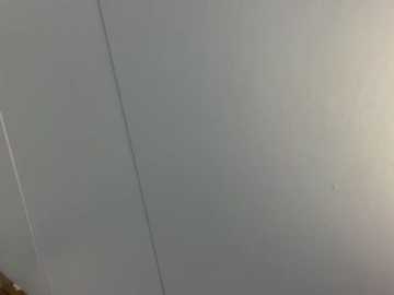 A video of a dimly lit room with a ceiling featuring a visible crack running horizontally. The walls and ceiling are painted in a neutral gray tone, giving a stark and minimalistic appearance. The lighting is soft, creating a subtle shadow effect.