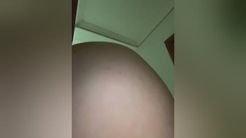 Media: Video of a modern architectural interior featuring a cylindrical pillar and green archway. The pillar has a smooth, light brown surface, and the archway is composed of three intersecting segments. The background is a muted beige, emphasizing the architectural elements.