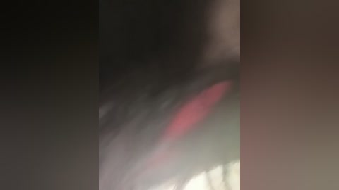 A blurry, dark video with a red glow in the bottom left, possibly from a fire or light source. The image is heavily pixelated, making details indiscernible.