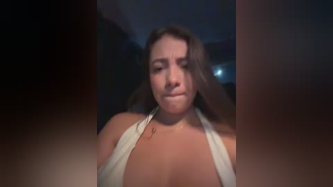 Media: A video of a young woman with long brown hair, wearing a white halter top, taken from a low angle, creating a dramatic, slightly blurred effect.