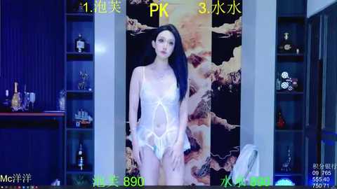 A video of a slender, fair-skinned woman with long black hair, wearing sheer white lingerie, standing in a dimly lit room with a marble-patterned wall and bookshelves in the background.