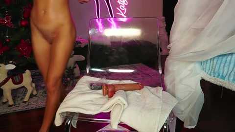 Media: A video depicts a nude man standing beside a transparent chair with a dildo on it; Christmas decorations adorn the background.