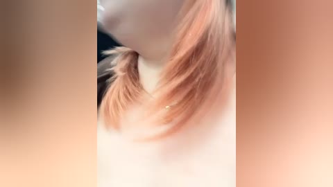 Media: A close-up video of a person's face with long, pastel-pink hair tied in a high ponytail, set against a blurred, peach-colored background. The skin tone is light and smooth.